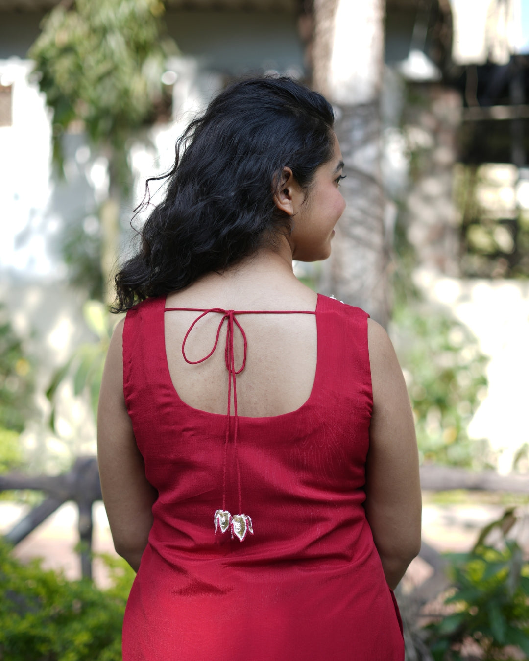 Woman wearing a red dress with an open back in a garden setting