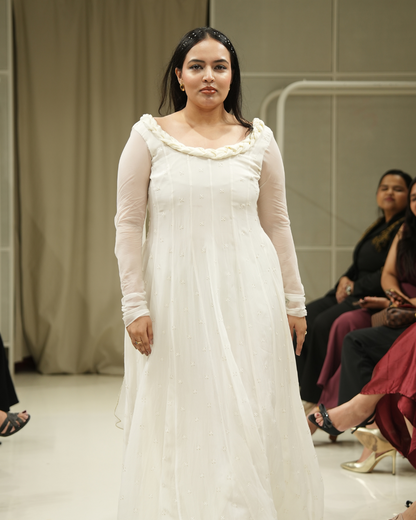 Woman in a white dress with long sleeves on a runway