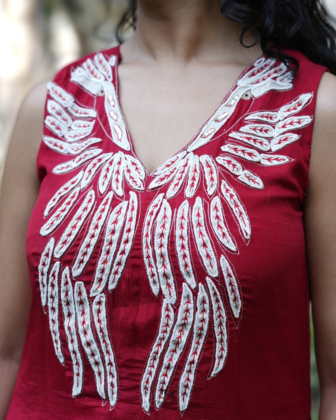 Red top with white floral embroidery on a blurred background