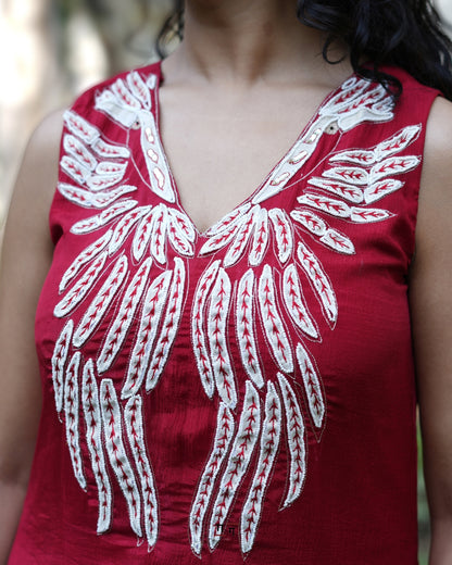 Red top with white floral embroidery on a blurred background