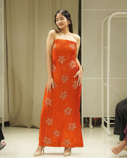 Woman wearing an orange floral dress standing indoors.