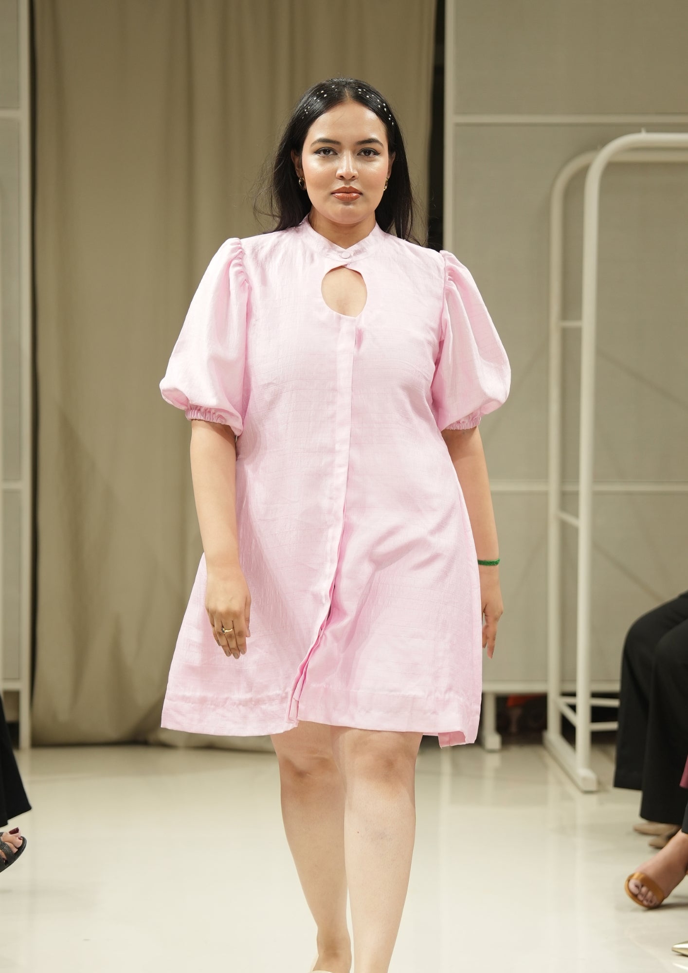 Woman wearing a pink dress with a cutout design on a runway.