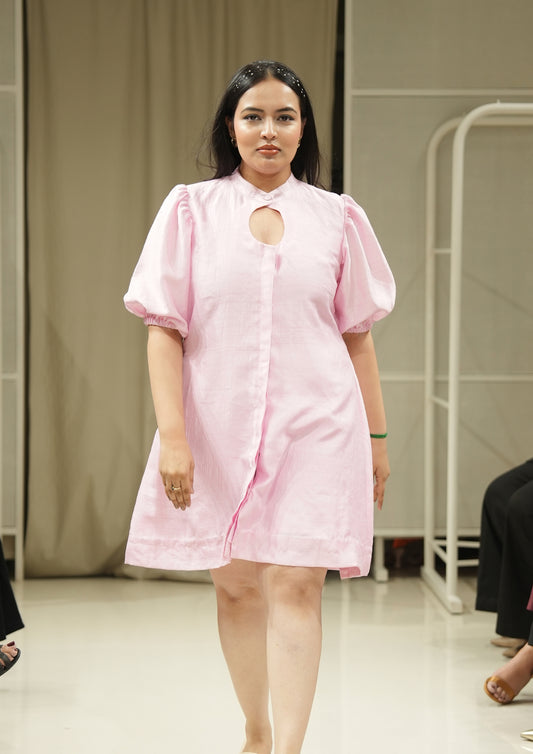 Woman wearing a pink dress with a cutout design on a runway.