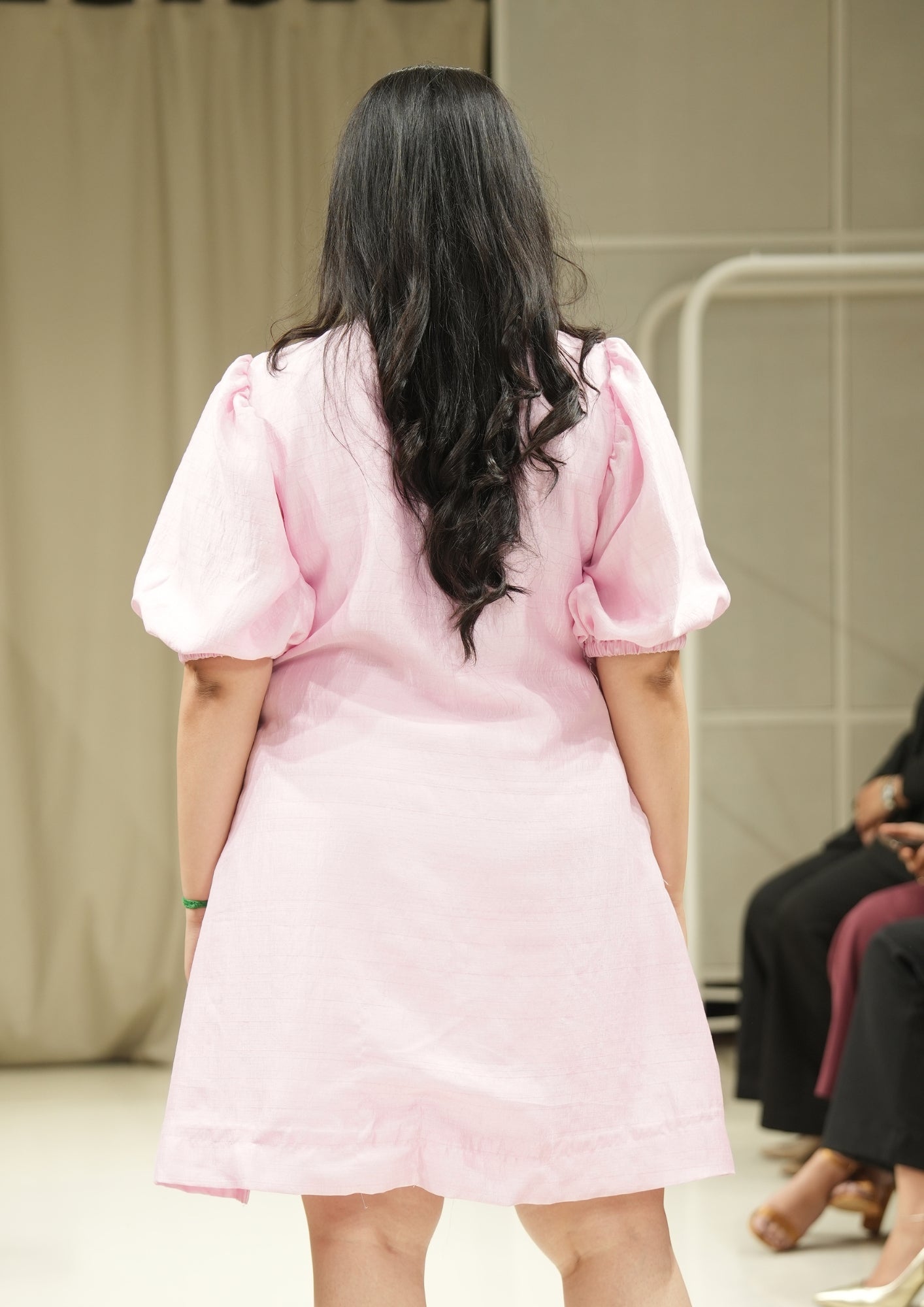 Person wearing a pink dress with puffed sleeves in an indoor setting.