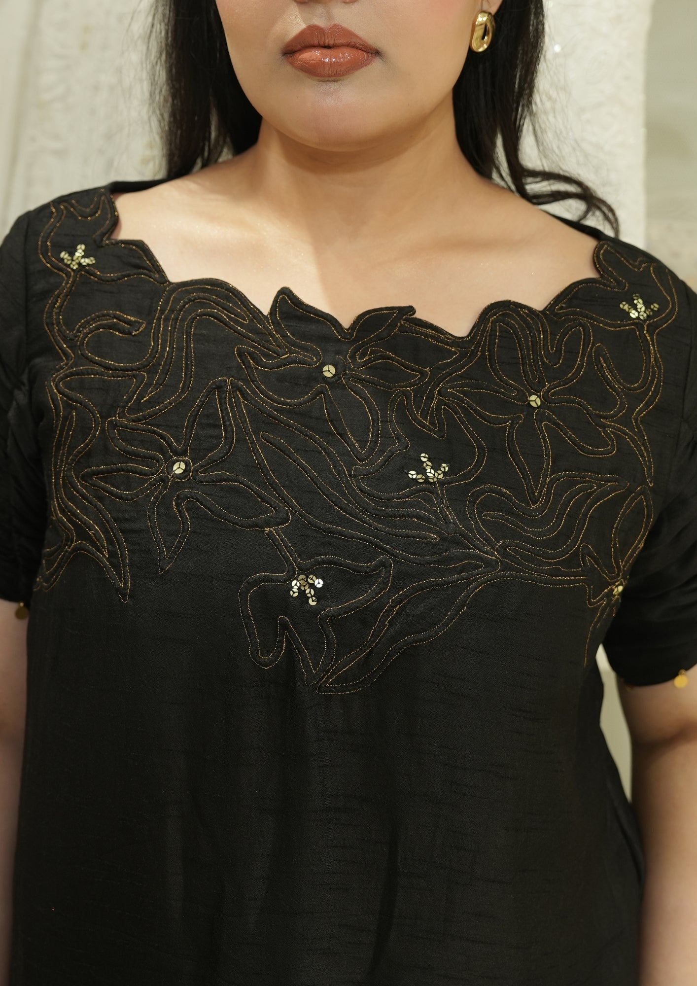 Black dress with gold embroidery on a plain background