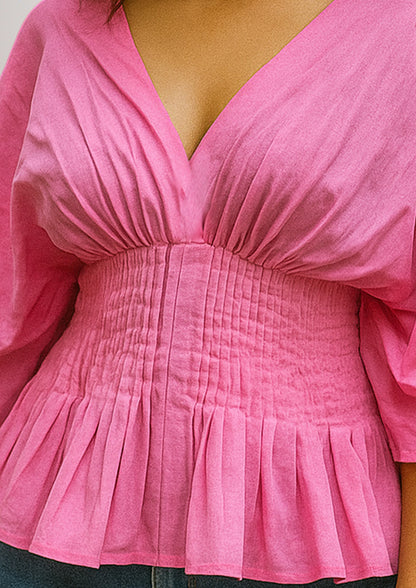 Close-up of a pink blouse with a pleated design