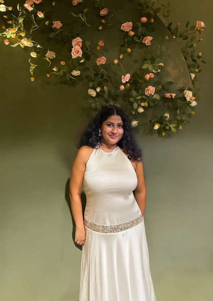 Woman in a white dress standing in front of a floral arch