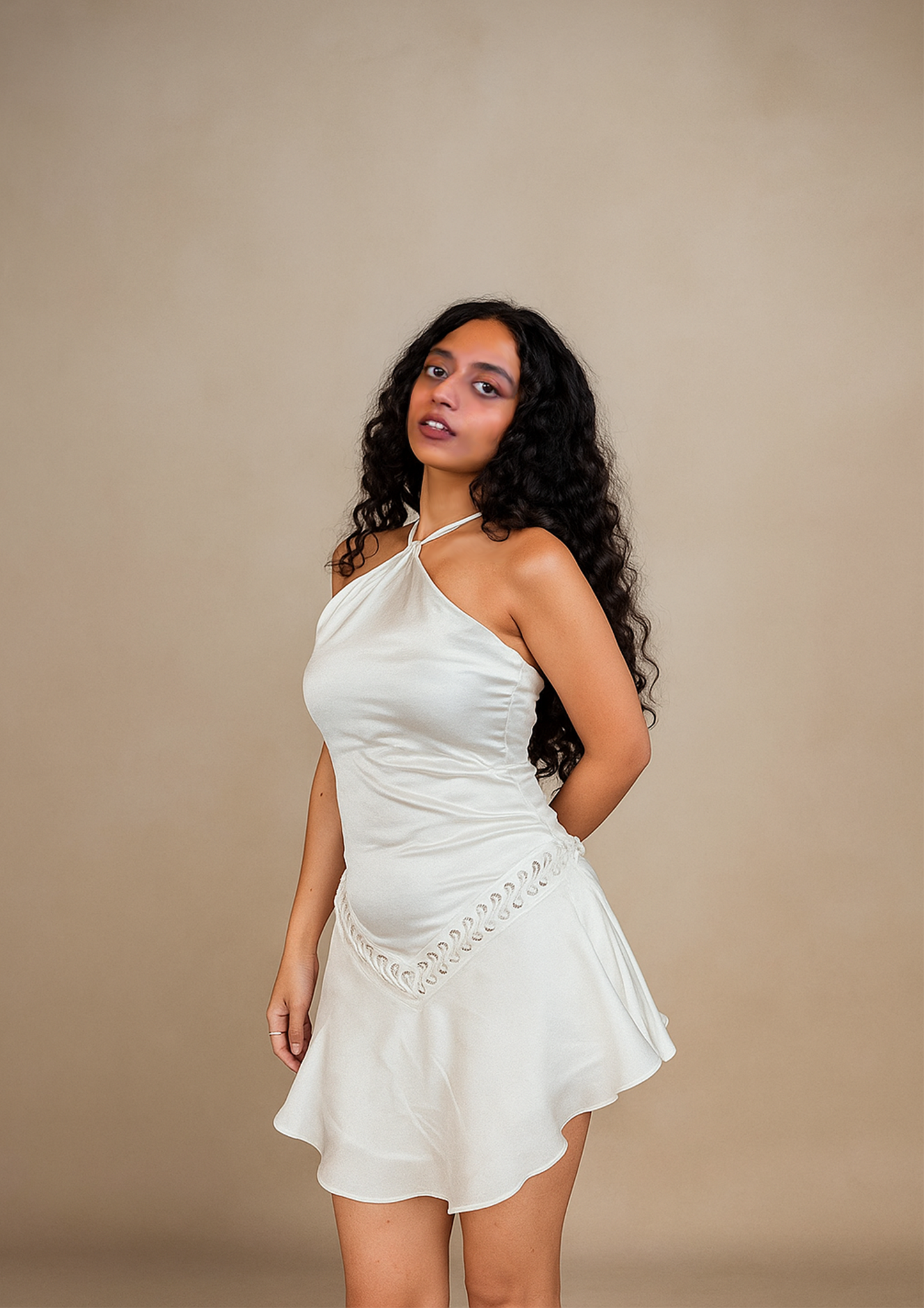 Woman wearing a white dress against a beige background